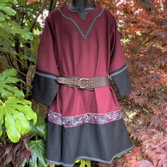 a woman's dress on display in front of some trees and bushes with leaves