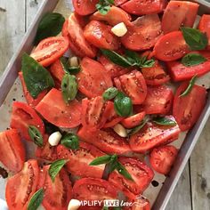 sliced tomatoes with basil and pine nuts on a baking sheet, ready to be cooked