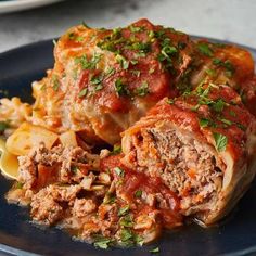 a blue plate topped with meat covered in marinara sauce and pasta next to a fork