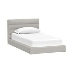 a bed with a white pillow on top of it and a gray headboard that has two pillows