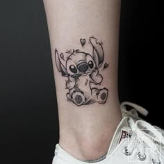 a small tattoo on the ankle of a person with a koala bear and hearts