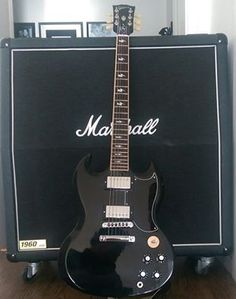 a black guitar sitting on top of a wooden floor