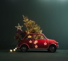 a small red car with christmas lights on it's roof and presents in the back