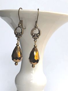 Antique bronze earrings feature brass Fleur de Lis connectors with vintage bronze fire polished faceted glass drops. Antique brass lever back earwires complete these brass Fleur de Lis earrings and they would be ideal for gift giving or anniversary gift, gift for mom, gift for girlfriend, or special occasion jewelry. We are proud to be part of the sustainable fashion movement by repurposing jewelry and components which would otherwise be discarded. We believe our company is responsibly reducing Gold Faceted Crystal Earrings For Gift, Bronze Metal Teardrop Earrings For Gift, Bronze Brass Earrings With French Hook, Bronze Nickel-free Drop Earrings, Nickel-free Brass Teardrop Crystal Earrings, Vintage Gold Crystal Earrings, Elegant Faceted Brass Earrings, Gold Faceted Brass Earrings, Victorian Gold Faceted Jewelry