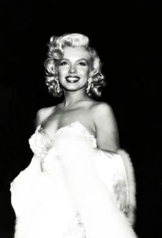 marilyn monroe in a white dress with fur stole around her waist and smiling at the camera