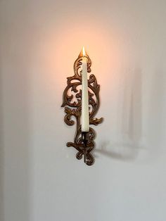 a candle that is on the wall next to a light fixture with an ornate design