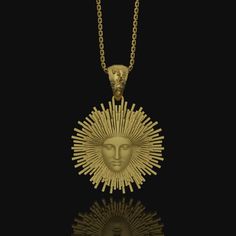 a gold necklace with an image of the sun in it's center on a black background