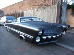 an old black car is parked on the side of the road