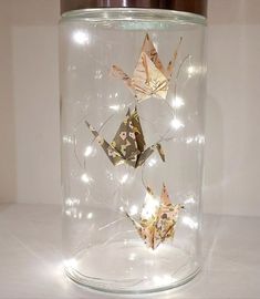 a glass jar with some origami in it and lights on the inside,