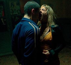 a man and woman standing next to each other in a room with posters on the wall