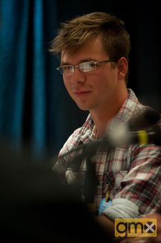 a man with glasses sitting in front of a microphone