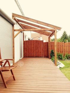 a wooden bench sitting on top of a wooden deck next to a white wall and fence