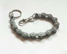 a close up of a bike chain bracelet on a white surface with a keychain