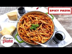 a large pot filled with pasta next to two slices of bread on top of a table