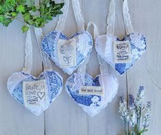 three blue and white heart shaped ornaments hanging on a wooden wall next to some flowers