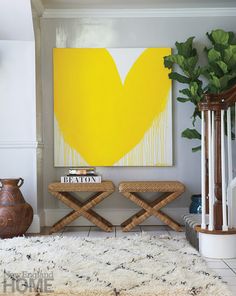 a living room with a painting and two stools in front of the rug on the floor