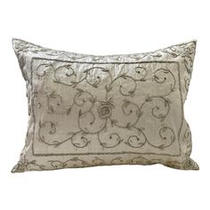 a white pillow with an embroidered design on the front and back, sitting against a white background