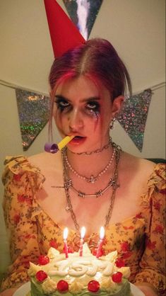 a woman holding a knife in front of a cake with candles on it and wearing a party hat