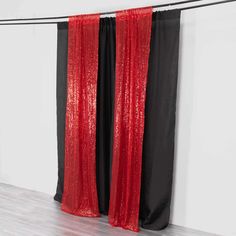 two black and red curtains are hanging in front of a white wall