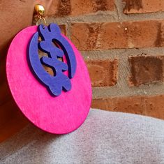 a person wearing a pink and purple earring with an image of a lizard on it