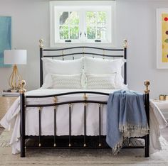 a bed with white linens and pillows in a bedroom next to a painting on the wall