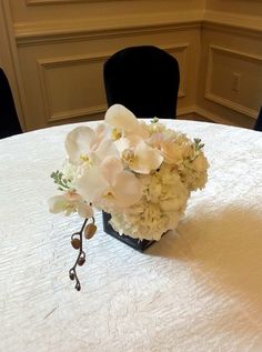 a bouquet of flowers sitting on top of a table next to a chair in a room