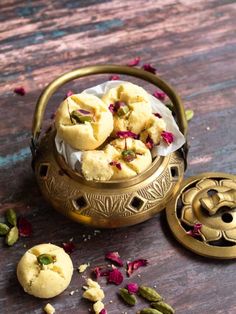 some food that is in a metal bowl on a wooden table with petals around it