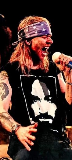 a man with long hair wearing a bandana singing into a microphone