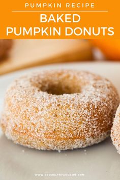 two sugared donuts sitting on top of a white plate next to an orange