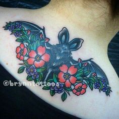 a bat with flowers and leaves on it's back shoulder, is shown in this tattoo