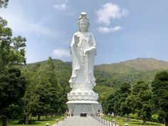 a large white buddha statue sitting in the middle of a park