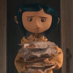 a doll with blue hair holding some papers