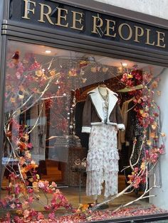 a storefront window with mannequins and flowers in the window display case