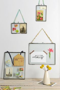 there are three pictures hanging on the wall above a vase with flowers and cards in it