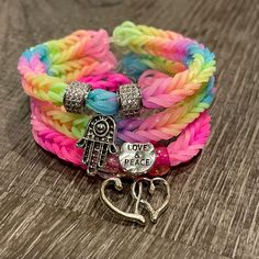 two bracelets with charms on them sitting on a wooden table next to each other