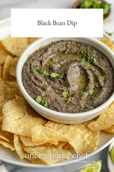 black bean dip in a white bowl surrounded by tortilla chips