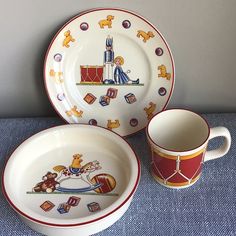 three plates and two cups on a blue table cloth with a dog theme painted on them