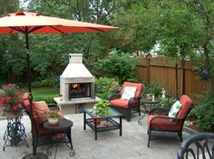 a patio with chairs, tables and an open fire place in the middle of it