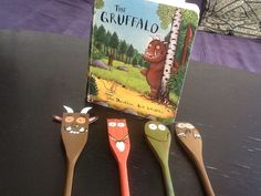 three wooden spoons are sitting on a table next to a children's book