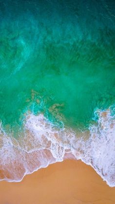 an aerial view of the ocean and beach with waves crashing on it's shore