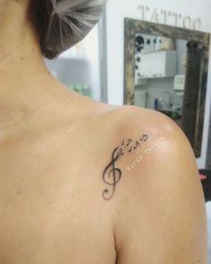 the back of a woman's shoulder with musical notes tattooed on her left shoulder