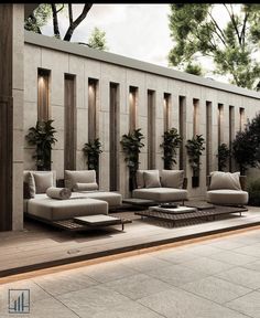 an outdoor living room with couches and tables on the ground near a wall covered in plants