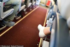 people sitting on seats in an airplane with their feet propped against the armrests