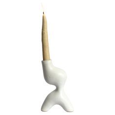 a small white candle holder with a wooden stick sticking out of it's side