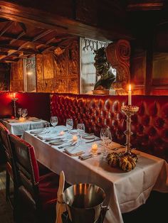 a dining room with red leather booths and white tablecloths set up for dinner