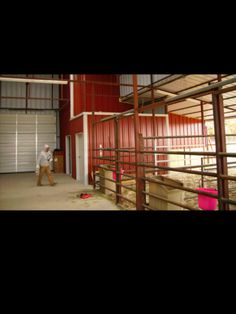 a man is walking in front of a barn with red walls and metal railings