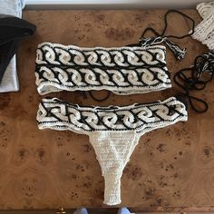 two pieces of crocheted clothing sitting on top of a wooden table next to shoes