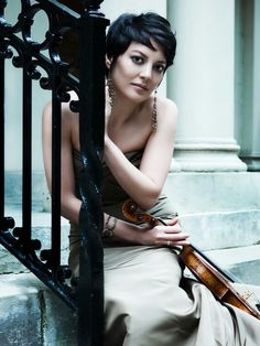 a woman sitting on the steps holding a violin