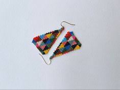 a pair of colorful beaded earrings sitting on top of a white table next to each other