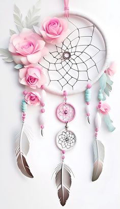 a white dream catcher with pink roses and feathers hanging from it's side on a wall